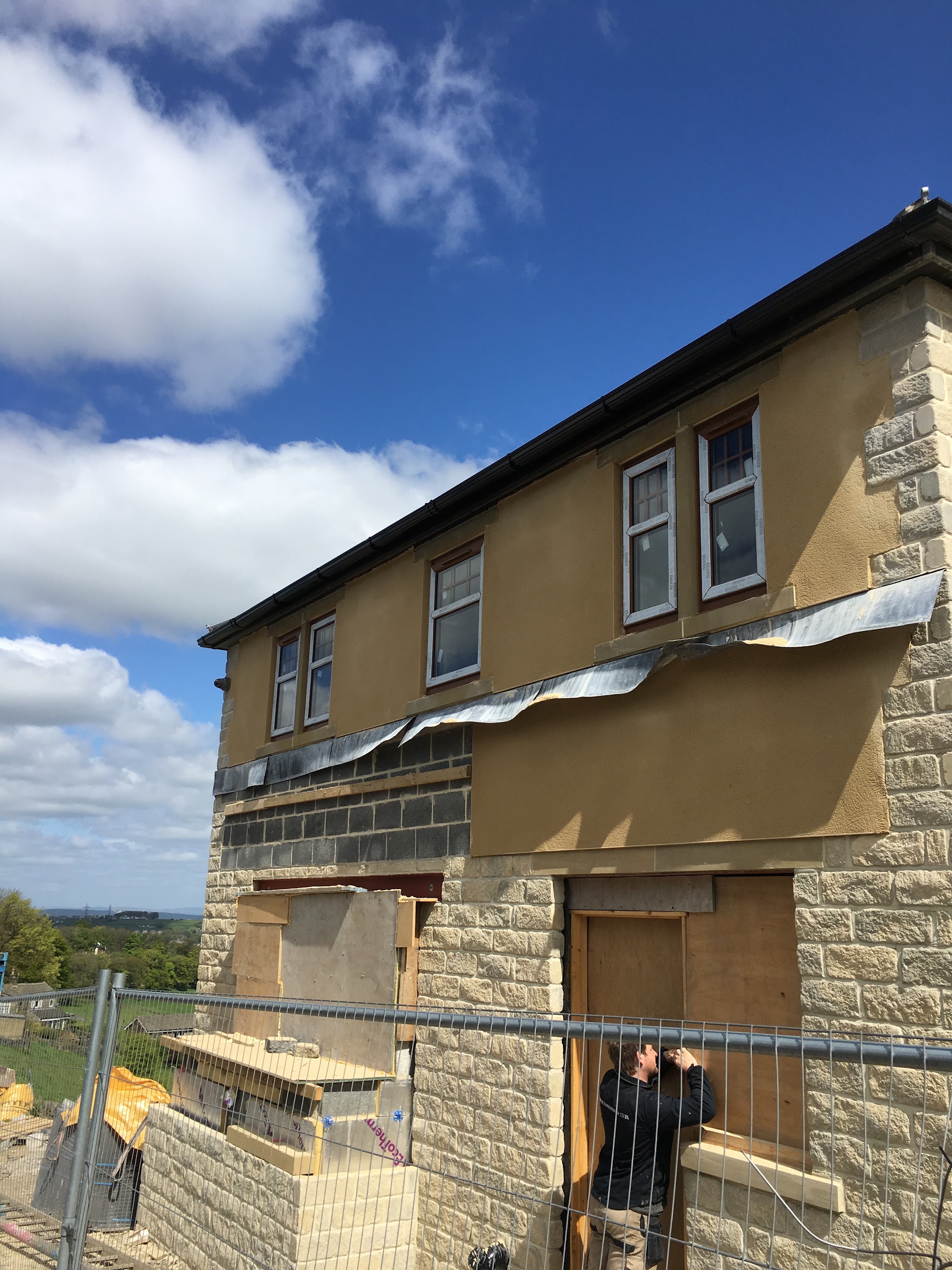 A newly finished upper facade on a stone building during ongoing construction
