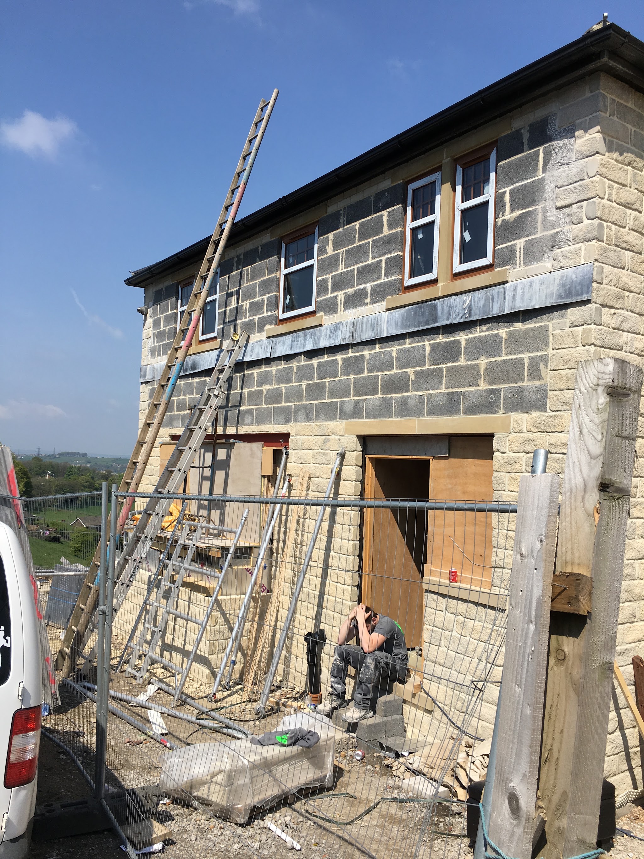 The stone building at an earlier stage of work, with exposed blockwork and ladders